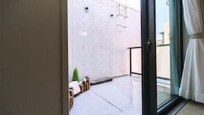 Ein modernes Zimmer mit einer Betongwand, einer Schiebetür aus Glas und einem kleinen Topfpflanzen.