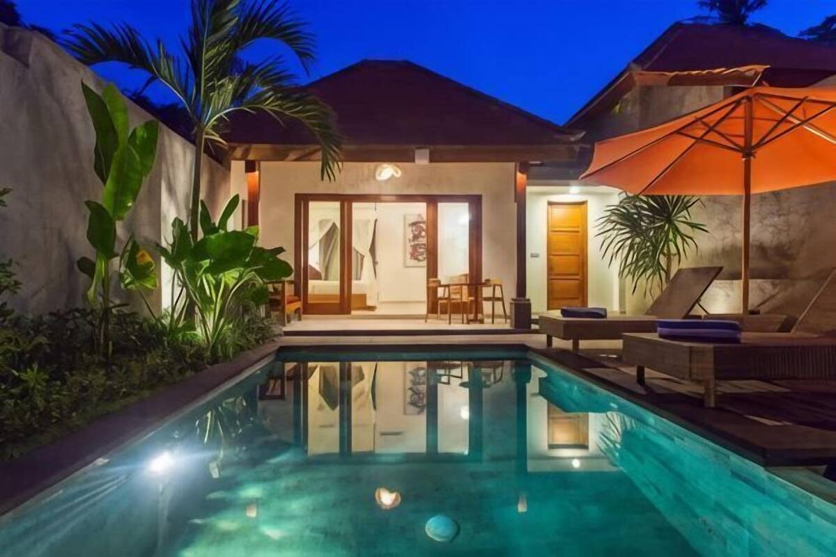 Área da piscina com piscina cristalina, espreguiçadeiras e um espaço de estar coberto.