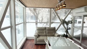 Un intérieur moderne avec un canapé, une table en verre et une vue sur un paysage enneigé, visible à travers de grandes fenêtres.