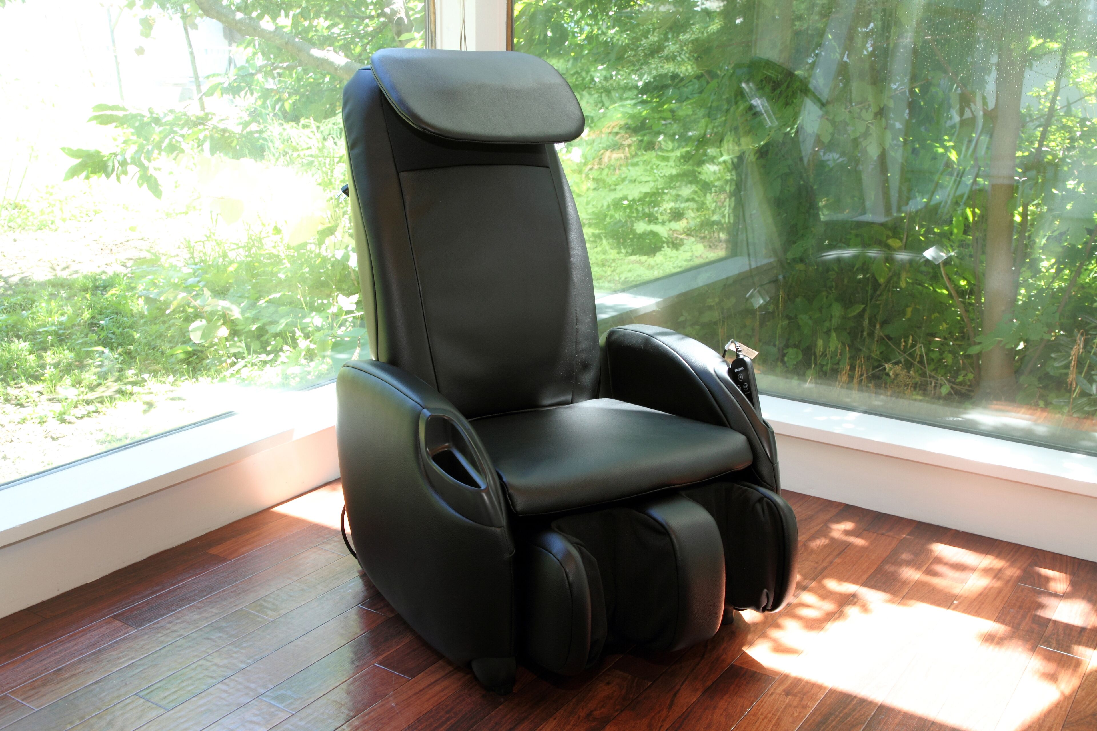 A massage chair in a room with a large window overlooking a garden.