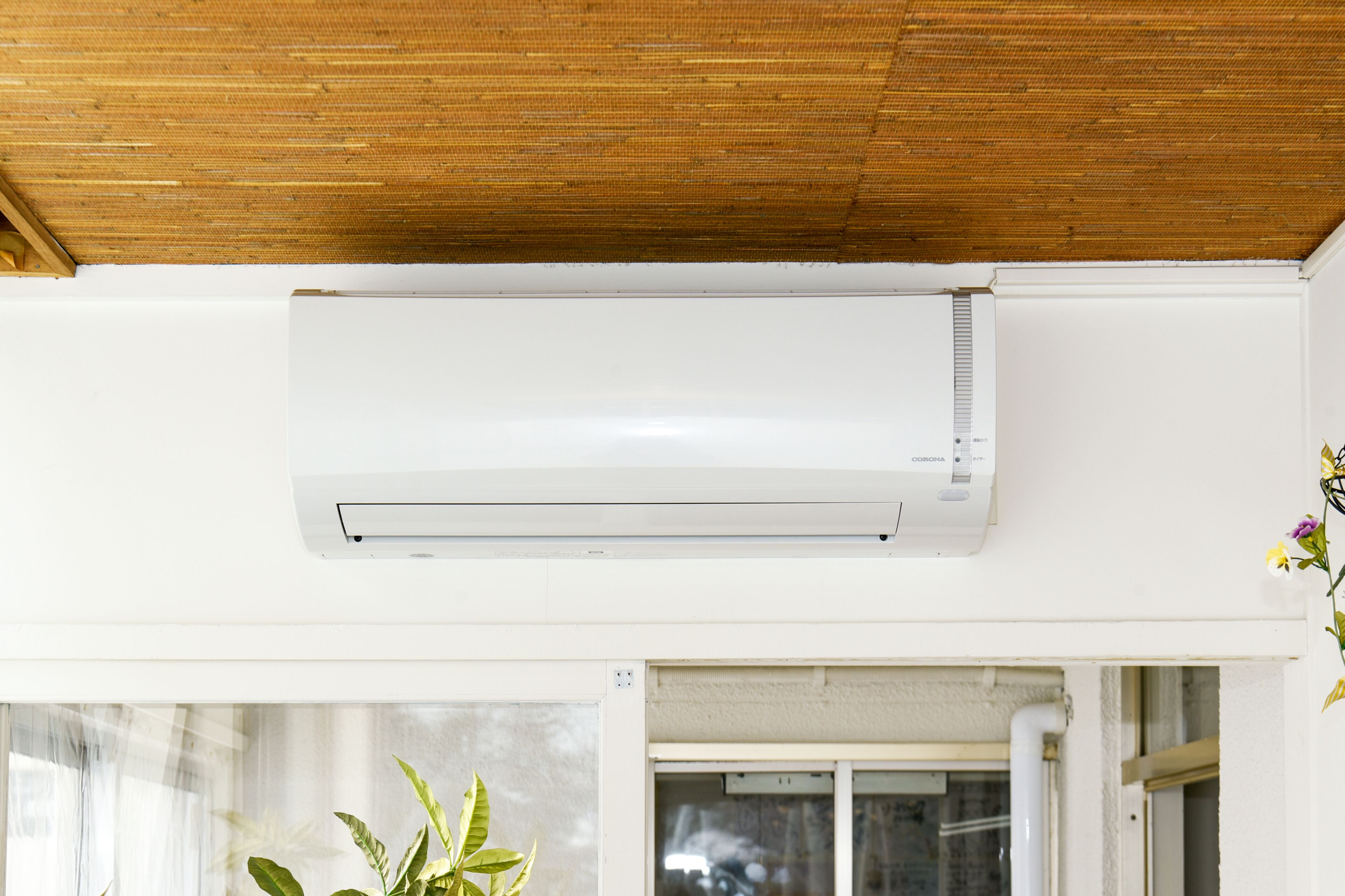 A room with a ceiling fan, a window with curtains, and a white air conditioning unit.