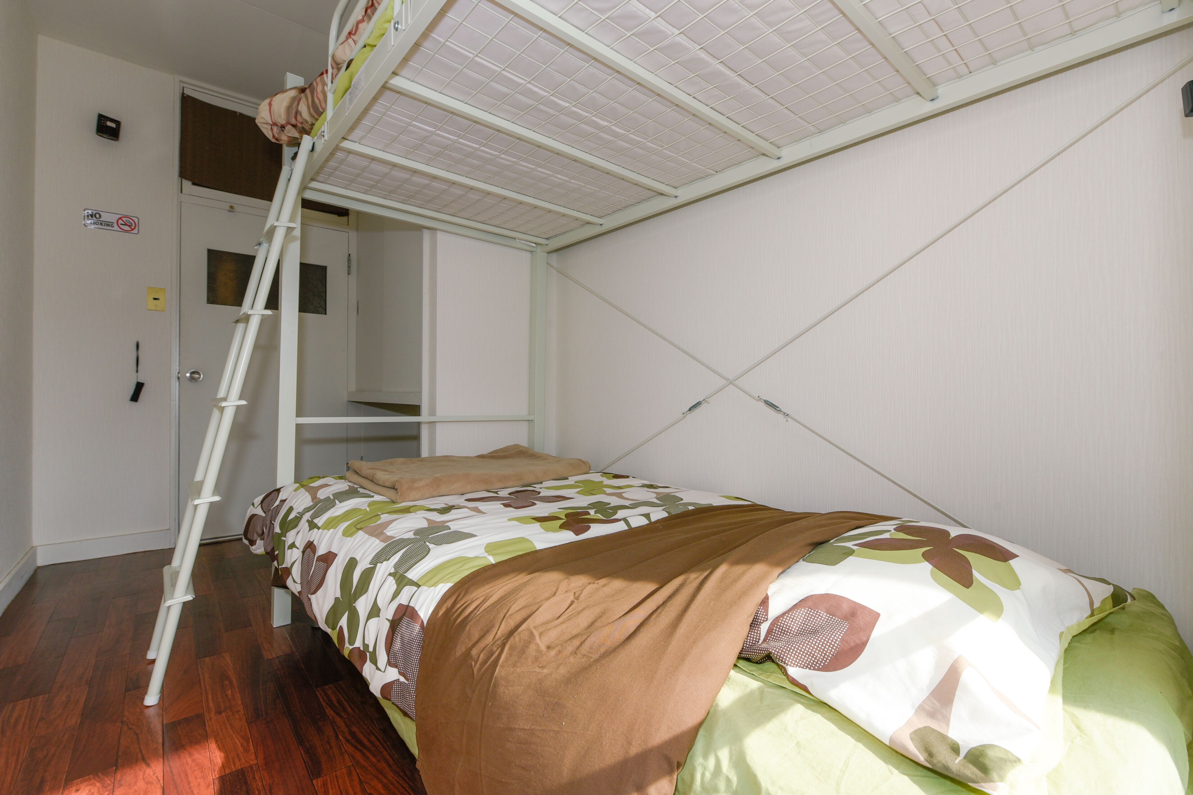 Een slaapkamer met een stapelbed, een ladder, een deur en een inloopkast.