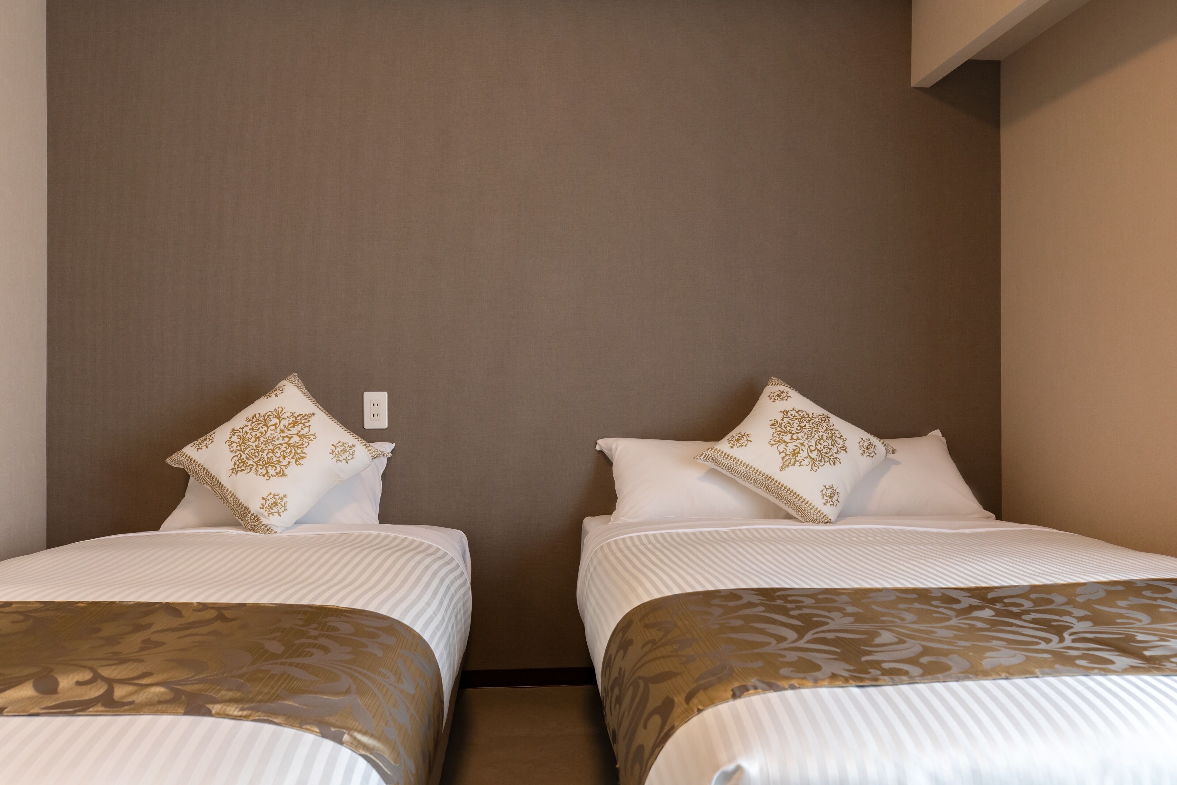 Een hotelkamer met twee enkele bedden, elk voorzien van een gebedde laken en passende kussens.
