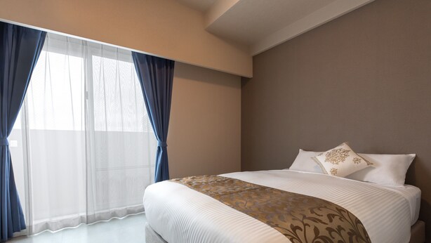 A hotel room with a large bed, a window with sheer curtains, and a view of the outdoors. - Mr.KINJO in GRAND BLUE CHATAN (Chatan)