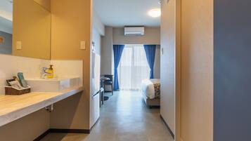Una camera d'albergo con bagno, un letto, una scrivania e una finestra con tende.