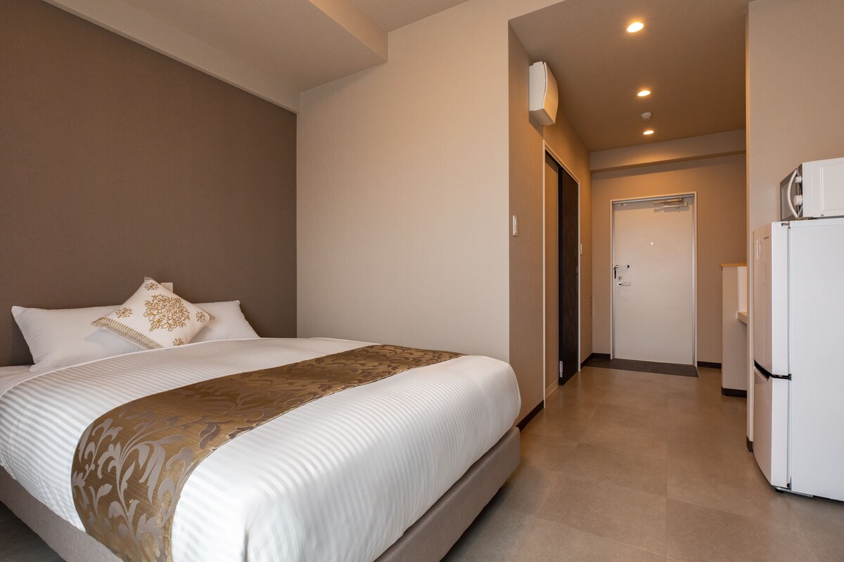 A hotel room with a large bed, a refrigerator, and a microwave.