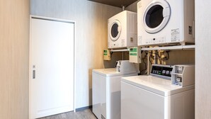A laundry room with two front-loading washing machines and a dryer, a control panel, and a door. - Mr.KINJO in GRAND BLUE CHATAN (Chatan)