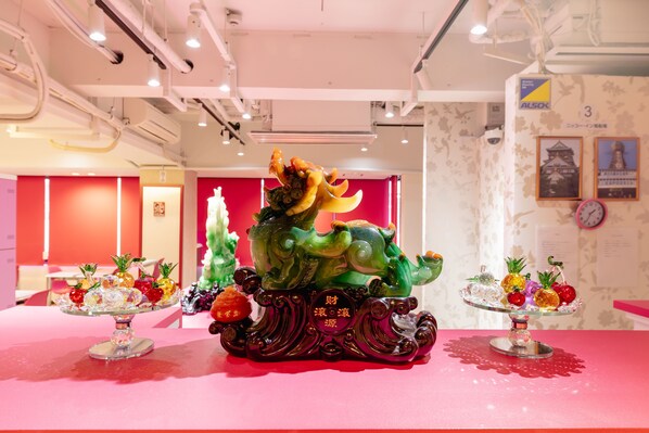 Una habitación con una mesa rosa, cristalería decorativa y una escultura de cerámica verde.