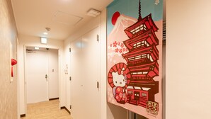 A hallway with wooden flooring, white walls, and a Hello Kitty-themed mural. - Nikko Inn Minamisenba 601 - Hostel, Caters to Women (Osaka)