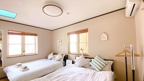 A hotel room with two beds, a wardrobe, a mirror, and a window. - Nestle Suite Tokyo Shinokubo (Tokyo)