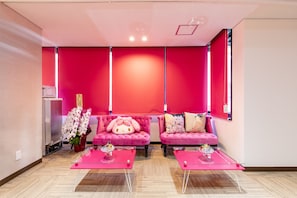 A room with two pink sofas, a glass coffee table, and a wall with a red panel. - Nikko Inn Minamisenba 602 - Hostel, Caters to Women (Osaka)