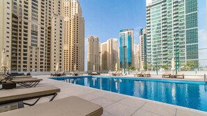 A rooftop swimming pool with lounge chairs and high-rise buildings in the background. - Maison Privee - Beautiful Chic Apt w/Full Marina View Nxt 2 Beach (Dubai)