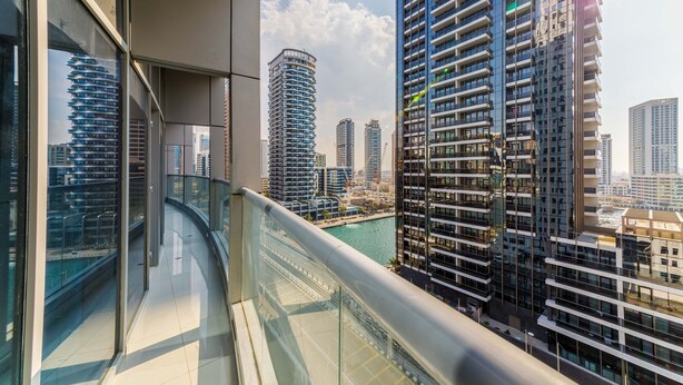 A modern high-rise building with a curved glass balcony overlooking a cityscape. - Maison Privee - Beautiful Chic Apt w/Full Marina View Nxt 2 Beach (Dubai)