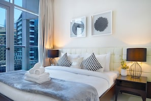 A modern hotel room with a large bed, a nightstand with a lamp, and two framed artworks on the wall.