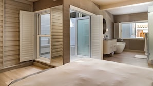 Ein modernes Schlafzimmer mit einem großen Bett, einem begehbaren Kleiderschrank und einem Badezimmer mit einer Badewanne.