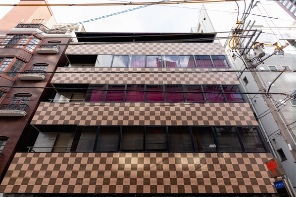 A multi-story building with a checkered facade, balconies, and visible electrical infrastructure. - Nikko Inn Minamisenba 702 (Osaka)