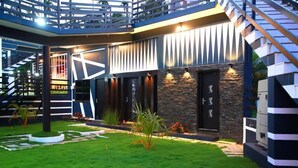 A modern building with a central courtyard, a staircase, and a stone facade. - Casa Lake View Resort (Vythiri)