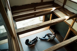 A high-ceilinged room with exposed wooden beams and a large window. - ume yamazoe (Yamazoe-mura)