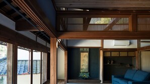 Una habitación tradicional japonesa con suelo de tatami, techo de madera bajo y puertas correderas.