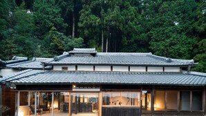 Una casa tradicional japonesa con techo de tejas, amplios ventanales y fachada de madera.