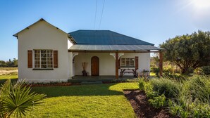 A single-story house with a gabled roof, a front porch, and a small garden area. - Karoohuisie (Kopanong)