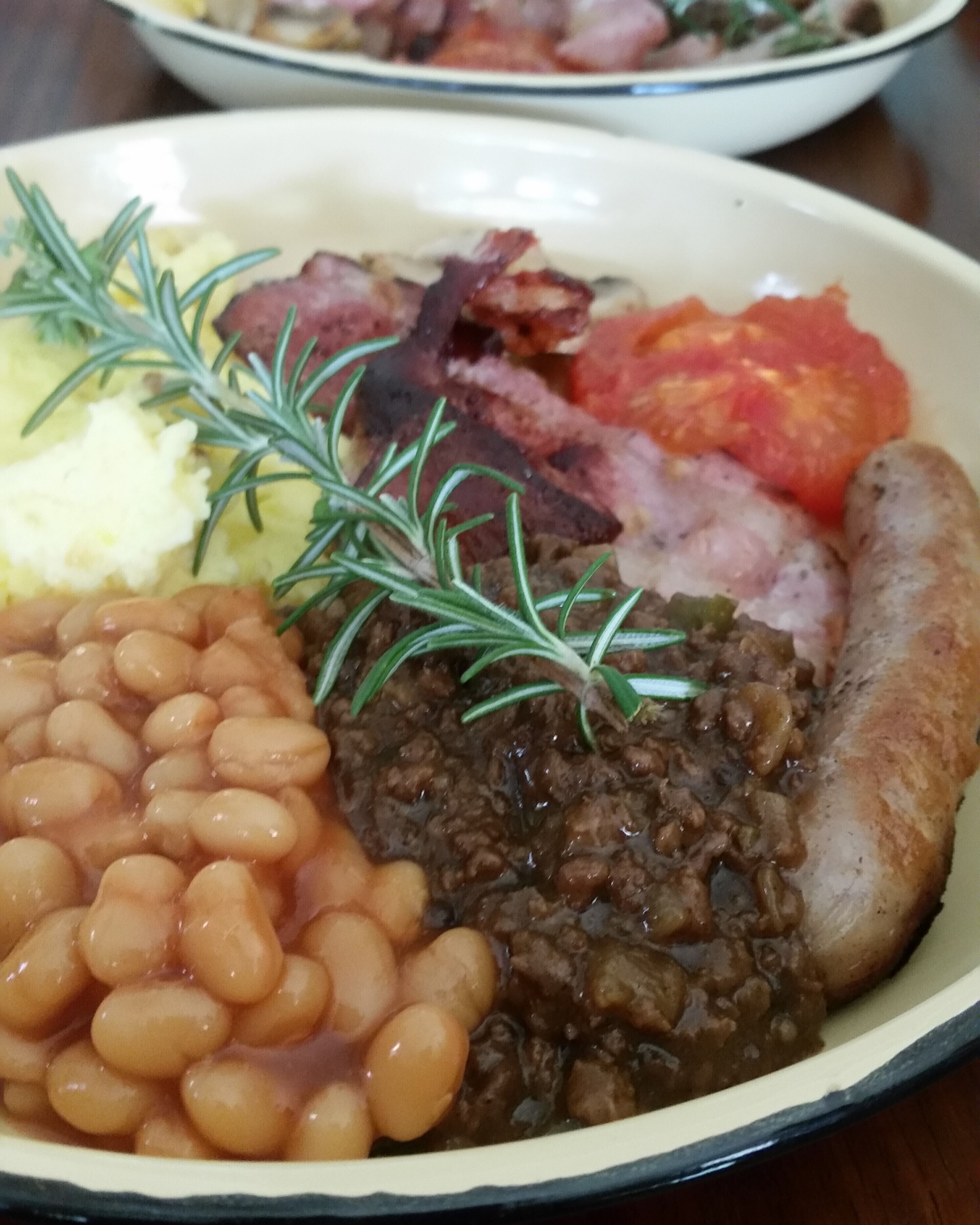 A plate of food with beans, meat, and vegetables.