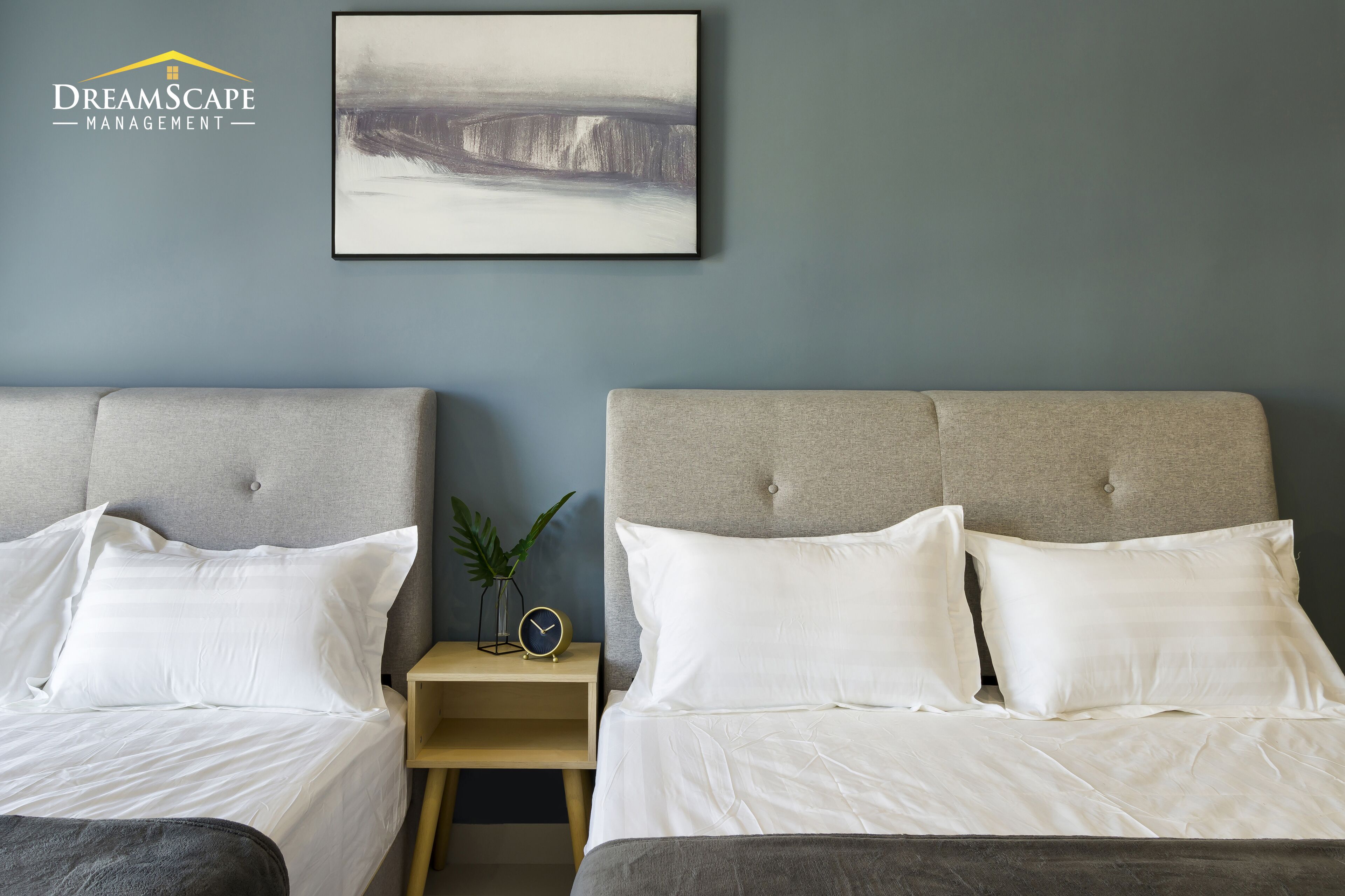 A hotel room with two beds, a nightstand with a clock, and a framed abstract painting on the wall.