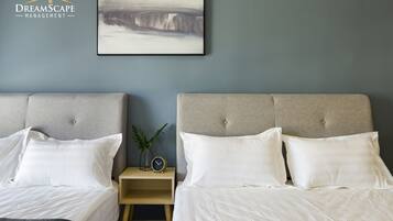 A hotel room with two beds, a nightstand with a clock, and a framed abstract painting on the wall.