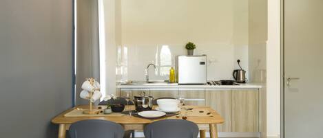 Uma cozinha moderna com mesa, cadeiras e geladeira.