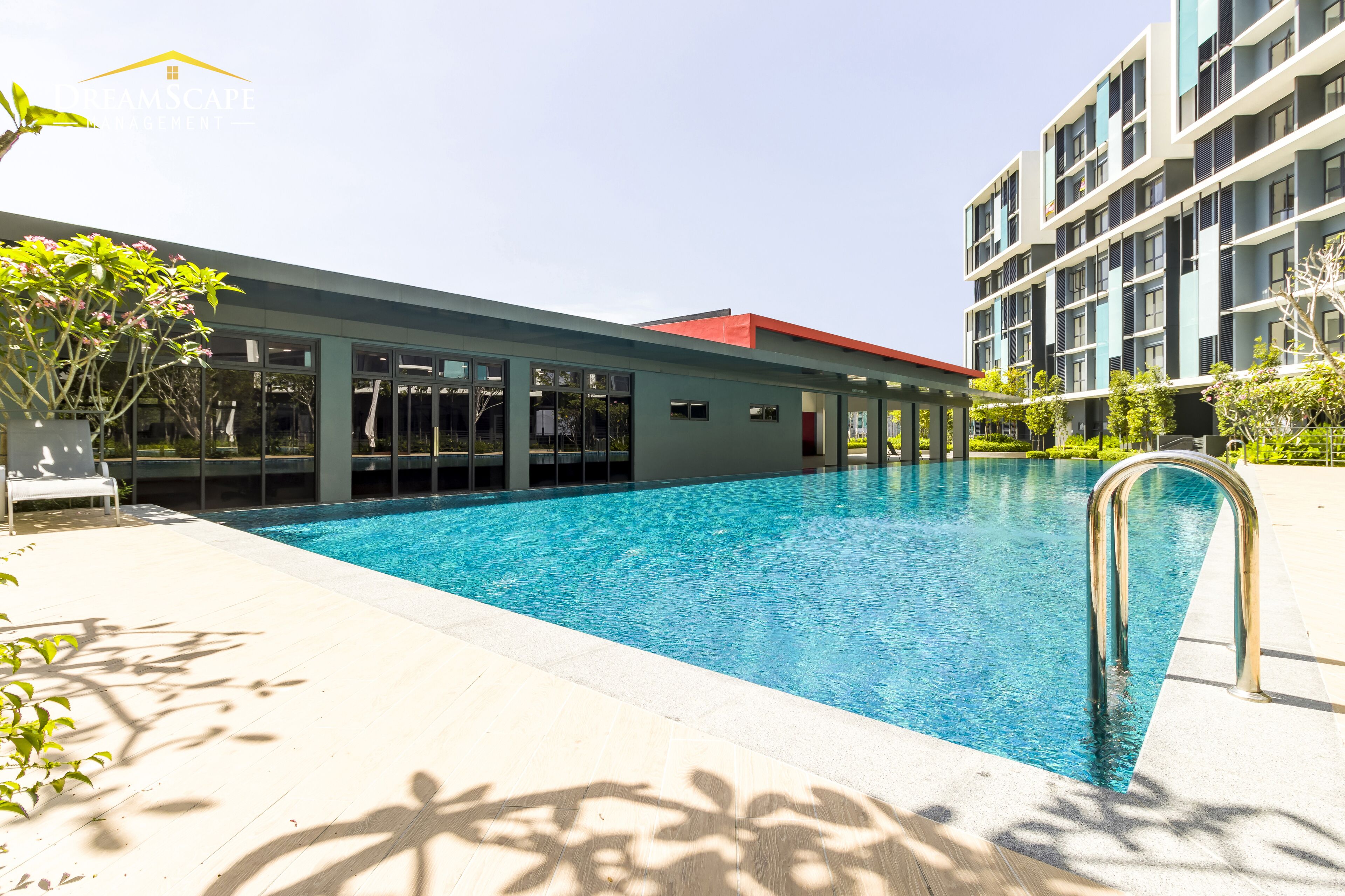 A modern building with a swimming pool, large windows, and a red roof.