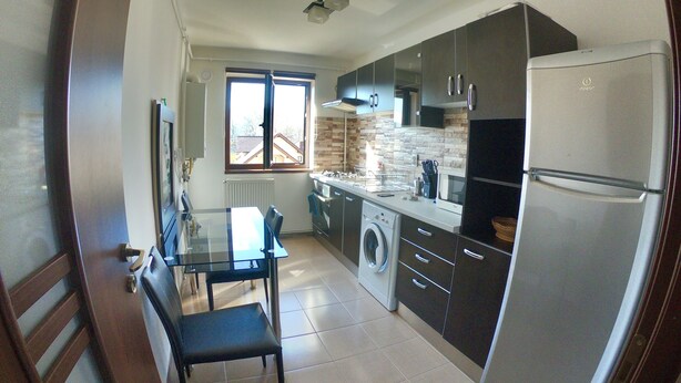 Una cocina moderna con refrigerador, lavadora y un comedor con mesa y sillas.