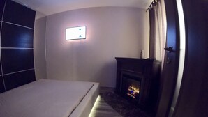 Un dormitorio moderno con cama, chimenea y panel de control en la pared.