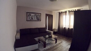 Una sala de estar con un sofá modular, una mesa de centro de vidrio y un cuadro en la pared.