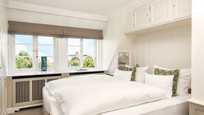 Una camera da letto con un letto grande, una finestra che si affaccia sul verde e mobili bianchi.
