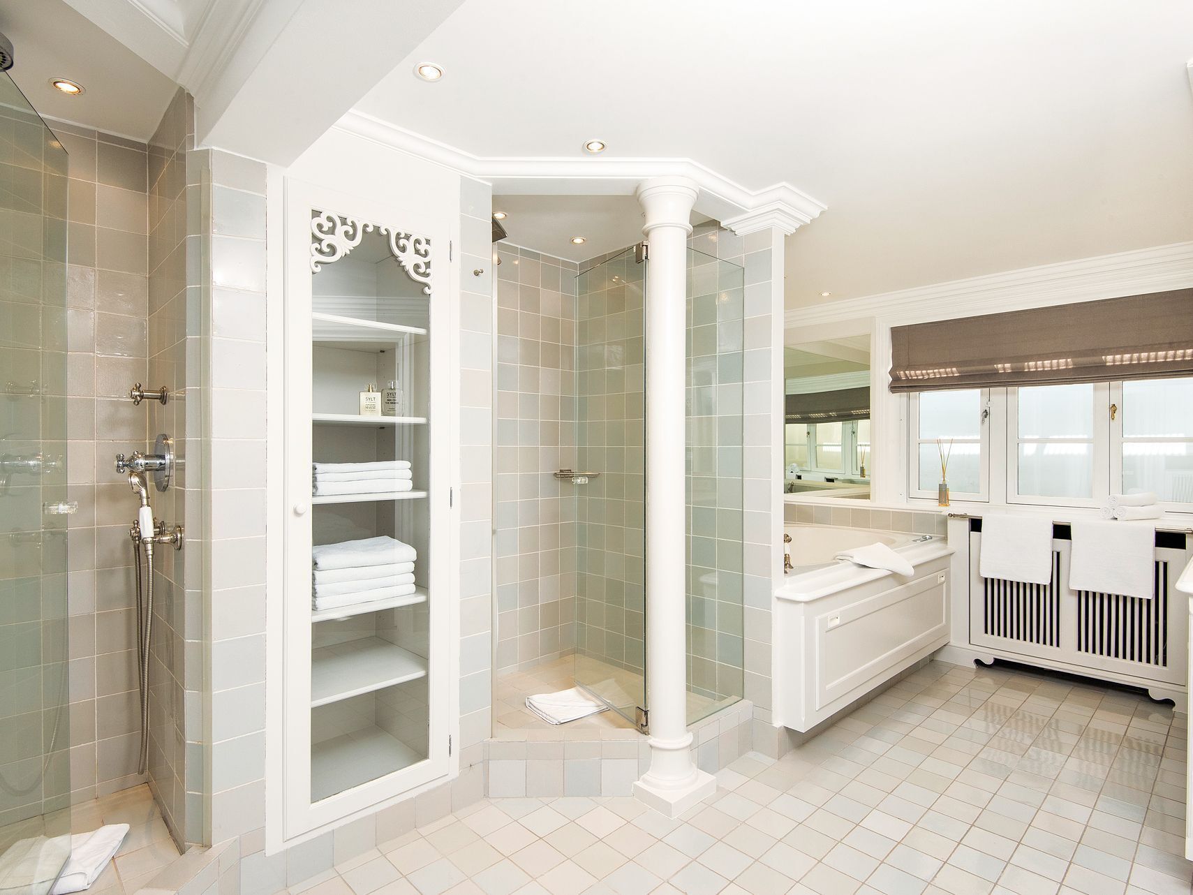 A modern bathroom with a walk-in shower, a glass-enclosed vanity, and a large mirror.