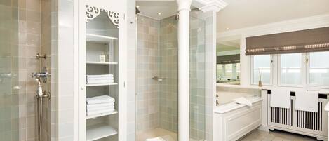A modern bathroom with a walk-in shower, a glass-enclosed vanity, and a large mirror.