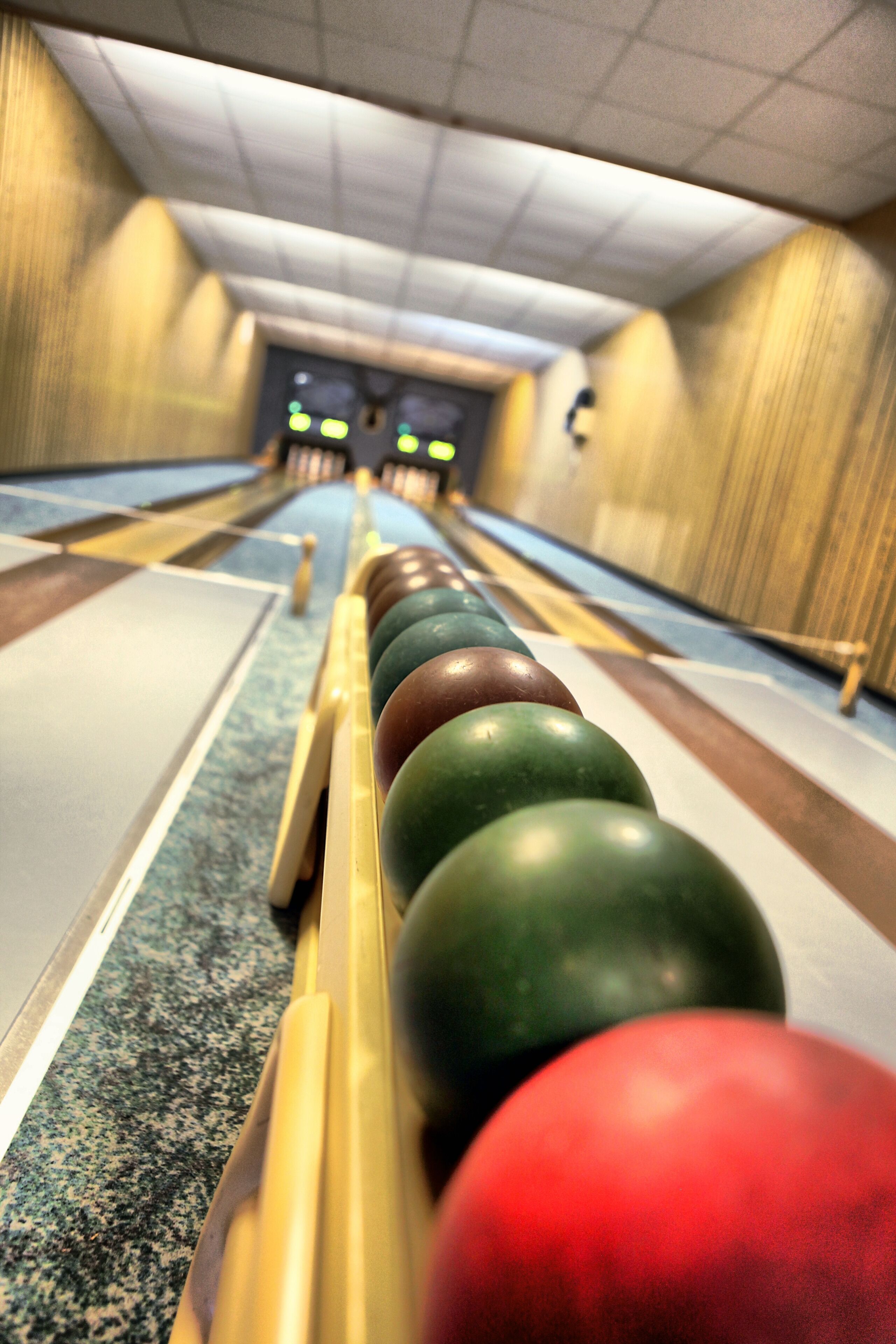Une salle de bowling avec une rangée de boules de bowling sur un présentoir.
