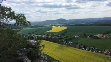 A rural landscape with fields, houses, and a mountain range in the background.