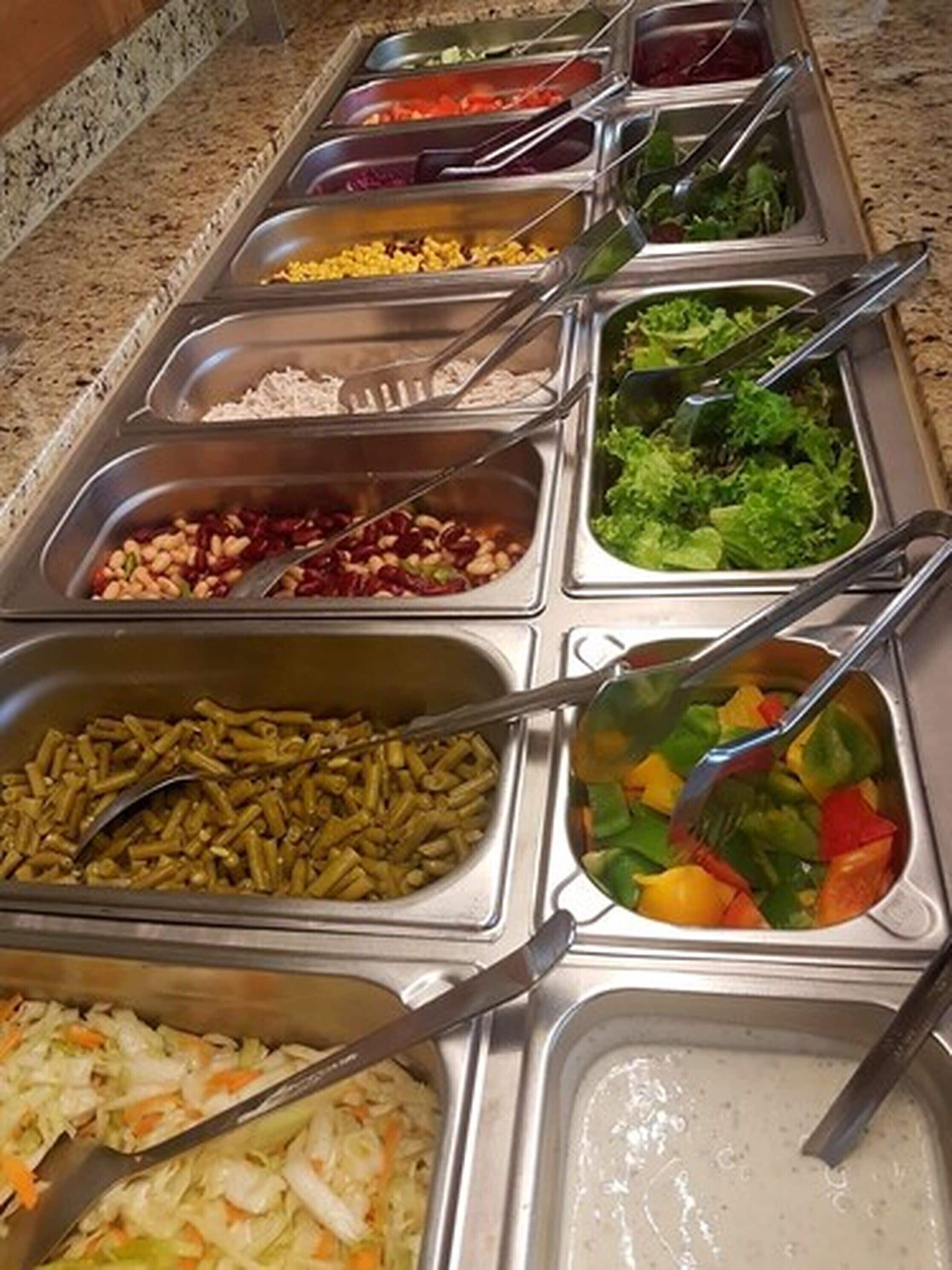 Un bufé con diversas opciones de comida, incluyendo pasta, ensalada y otros platos.