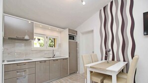 A modern kitchen with a built-in microwave, a window, and a dining area with a table and chairs. - Holiday apartment modernly furnished only 300 m from the sea (Baška)