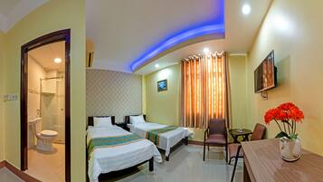 A hotel room with two beds, a shower, a dining area with a table and chairs, and a TV on the wall.