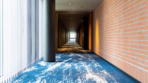 A corridor with a blue carpet, brick walls, and a column.