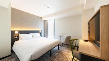 Una habitación de hotel con una cama grande, un escritorio, una silla, un televisor y una mesita.