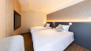 A hotel room with two beds, a flat-screen TV, a wooden accent wall, and a modern light fixture.