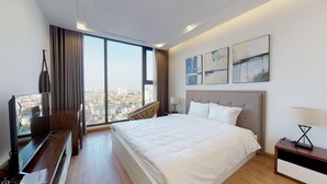 Habitación de hotel moderna con una cama grande, televisión y vistas a la ciudad.