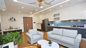 Una sala de estar moderna con un sofá, dos sillones, una mesa de centro y un comedor con mesa y sillas.