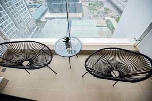A balcony with two black wire chairs and a small round table with a potted plant.
