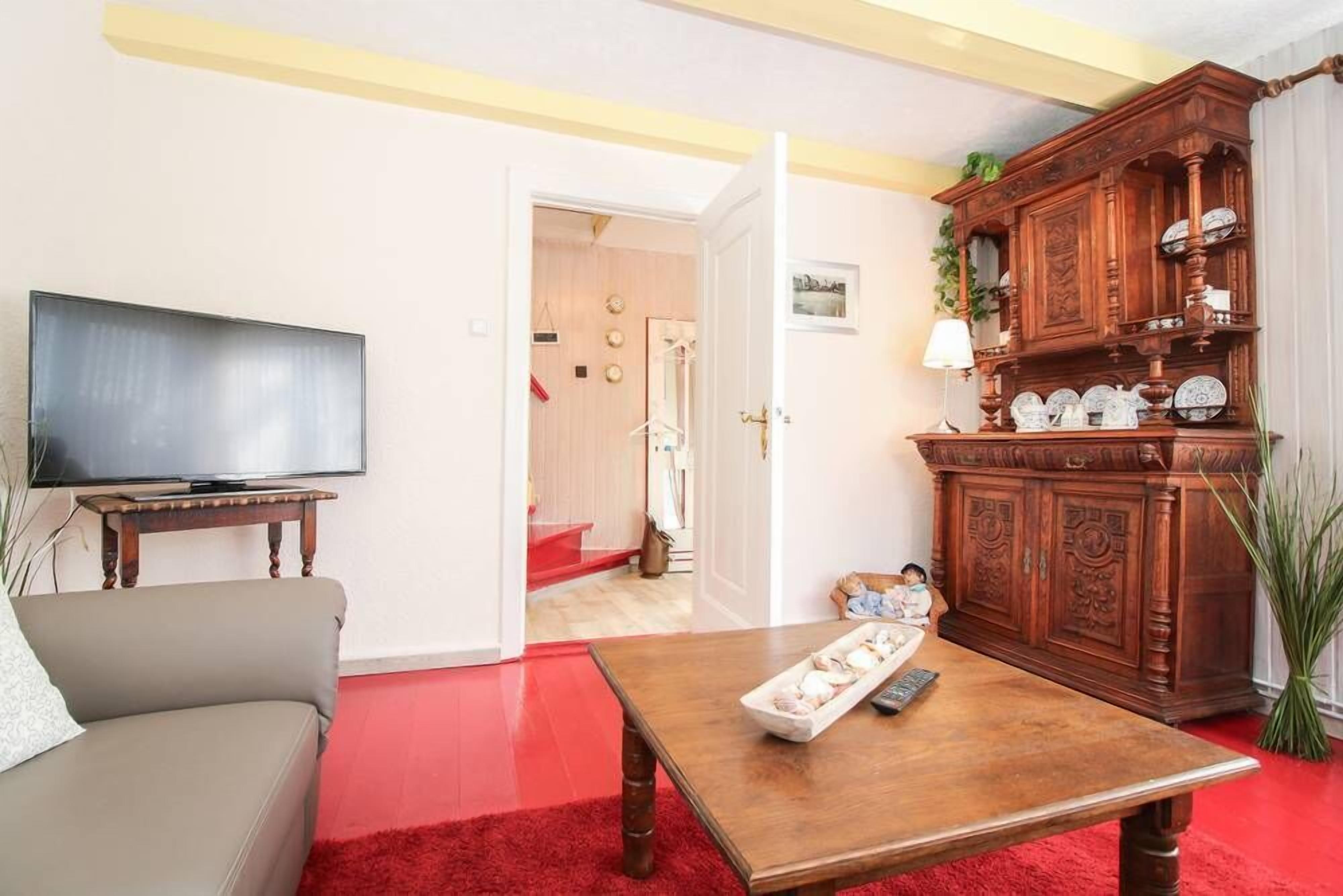 A living room with a sofa, a coffee table, a TV, and a wooden cabinet.