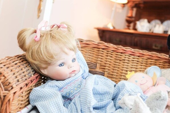 A doll in a wicker basket with a checkered cloth.