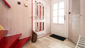 A hotel hallway with a wooden floor, a red and white elevator, and a door with a window.